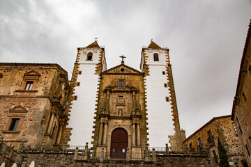 Fachada y acceso a Iglesia de torres de piedra con fachada blanca en Cáceres