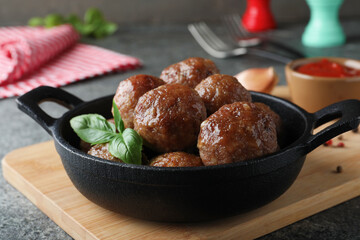 Tasty cooked meatballs with basil on grey table, closeup