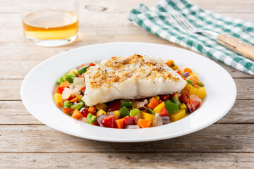 Grilled cod with vegetables in plate on wooden table	
