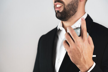 Unrecognizable young man with beard applying cologne.