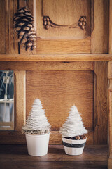 Two mini DIY paper trees Christmas decoration with natural moss on wooden cupboard