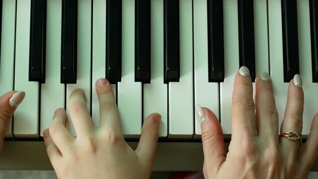 Playing the piano in the family circle theme. Close-up of the hands of a child and a woman playing the piano keys.Teaching a child to play musical instruments.Music lessons at school. Creativity