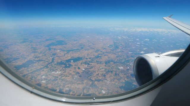 Passenger plane fly over western France, Thouars commune and Deux-Sevres department seen down through cabin window. Jet engine inlet and wing on right side