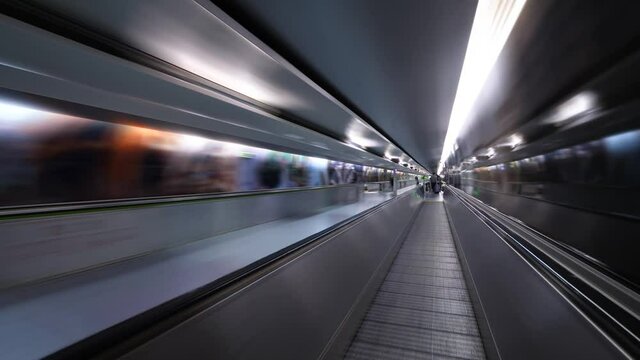 First person view time lapse shot, stand at first and walk forward second travolator, Long tunnel, blurred motion, people silhouettes pass by and stay on the way