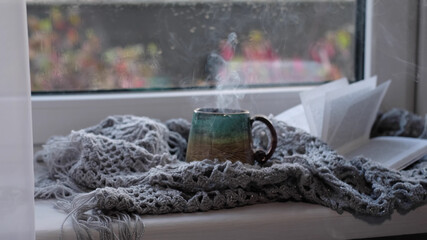 Fototapeta na wymiar Steaming coffee cup on a rainy day window background. cozy atmosphere, in cold weather. Rainy Day Mood. warming home atmosphere