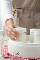Woman making tasty yogurt at table, closeup