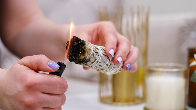 Female hand sets fire to incense on a copper bowl. Aroma therapy, to relax after a hard day. Smells for concentration, purification and clarification of consciousness.
