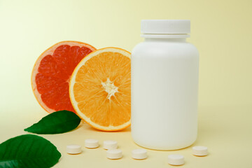 Vitamins from foods or supplements choices. Vitamin c tablet spilling out of white plastic bottle with fresh juicy orange fruits and green leaf. natural supplements for healthy good life
