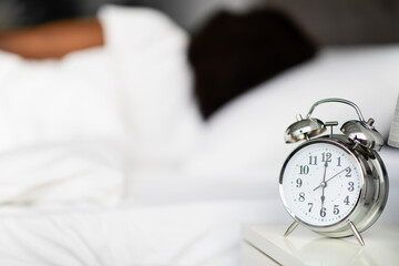 Alarm on bedside over unrecognizable sleeping black lady