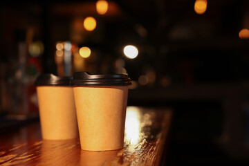 Paper coffee cups on wooden table in cafe. Space for text
