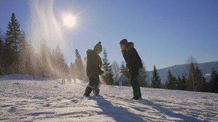 Mother and son playing with snow on the winter mountain. Happy family plays together outside. Winter family activities.