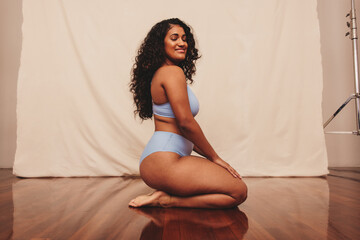 Smiling young woman kneeling in blue underwear - Powered by Adobe