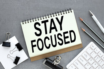 STAY FOCUSED table with open notebook, glasses, white keyboard