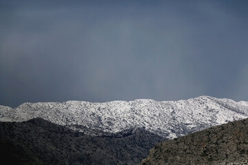 Mountain peak covered in snow and overcast sky. 