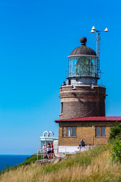 Kullaberg fyr, old lighthouse on the cliffs of Kullaberg naturreservat on the Swedish west coast. Lighthouse on the rocks viewing out into the baltic sea. Warm summer, high cliffs, deap ocean. Trees