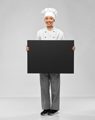 cooking, advertisement and people concept - happy smiling female chef holding big black chalkboard over grey background