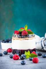 Parfait with cream or yogurt, jam and fresh berries in the glass jar. Close up. Healthy dessert or snack.