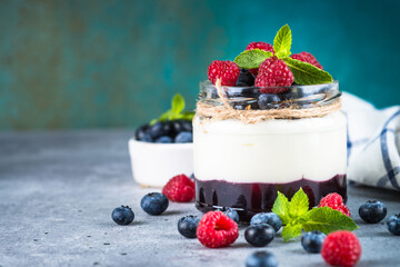 Parfait with cream or yogurt, jam and fresh berries in the glass jar. Close up.