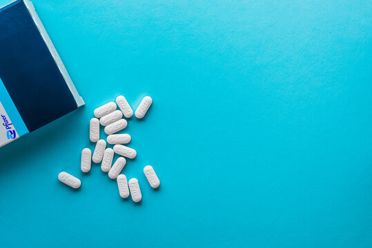 Pfizer Covid-19 Paxlovid treatment box and pills isolated on a blue background.