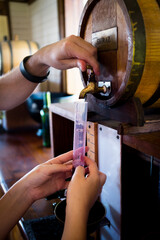 Two people taking a red wine sample for testing.