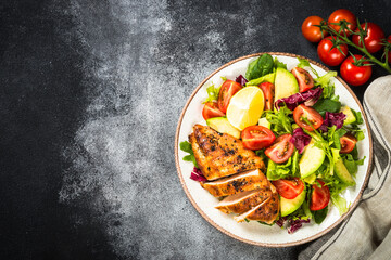 Healthy food concept. Grilled chicken with fresh salad at black background. Top view with copy space.