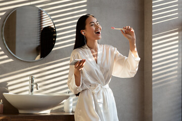 Happy korean woman singing while brushing teeth at bathroom