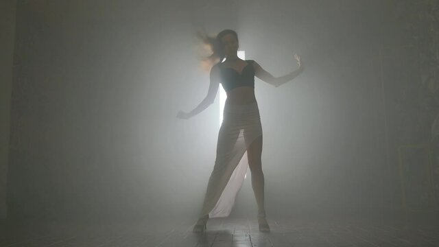 Woman dancing bachata dance indoors with smoke.