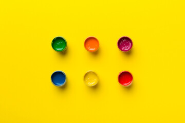 jars with gouache of different colors on Colored background. hobby painting. Top view with empty space. workplace for creativity. home teaching concept drawing