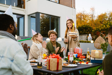 Multiracial friends making fun during birthday party on backyard