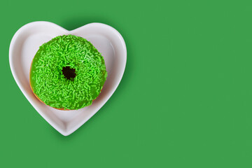 Green donut in a plate in a shape of a heart