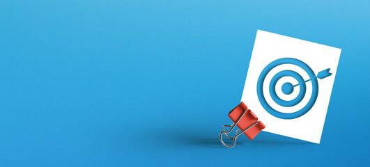 Metal clip with target sign on paper on blue background