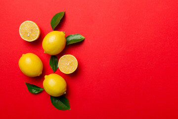 Many fresh ripe lemons with green leaves on colored background, top view, space for text