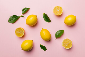 Many fresh ripe lemons with green leaves on colored background, top view, space for text