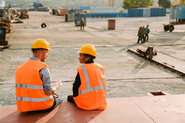 Multiracial man and woman talking while working together at port