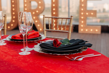 Guests table setting for banquet in black, red and gold style. Elegant dinner: decor, tablecloth,...