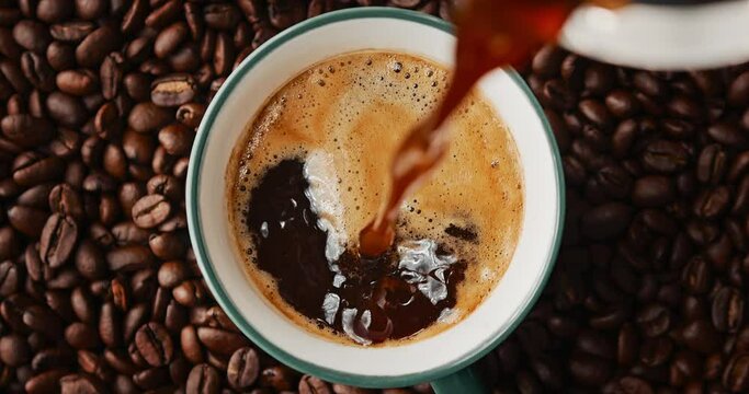 brewed coffee in a geyser coffee maker is poured into a coffee mug, top view, slow motion