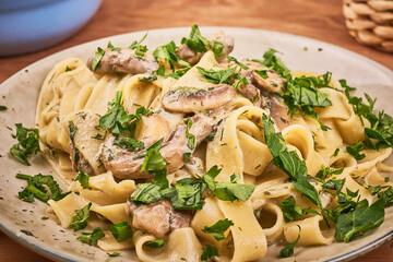 Fettuccine with mushroom sauce and fresh parsley in a plate, close-up - pasta with mushrooms and cream, traditional italian cuisine