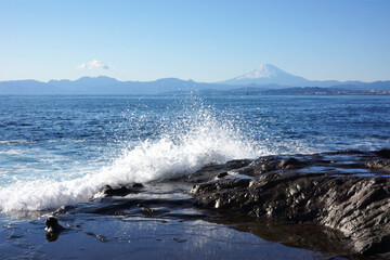 江ノ島の岩場海岸の波しぶきと富士山