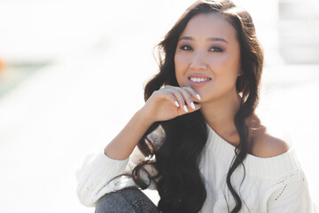 Beautiful woman outdoors. Pretty lady on urban background. Asian female closeup portrait.