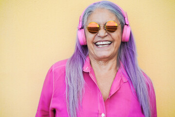 Happy senior woman listening to playlist music with headphones - Focus on face