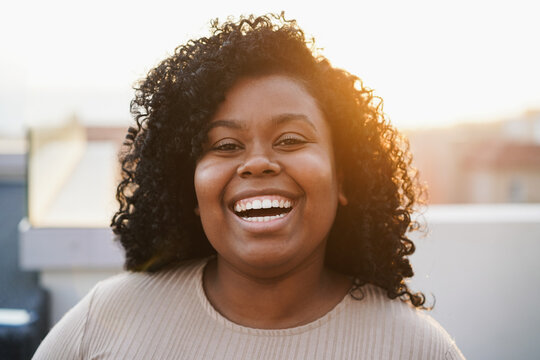 Young african woman smiling on camera with sunset on background - Focus on face