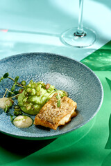 Fried cod with mashed peas and truffle oil. Bright backgrounds. Hard shadows, selective focus.