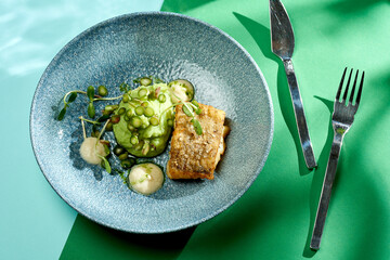 Fried cod with mashed peas and truffle oil. Bright backgrounds. Hard shadows, selective focus.