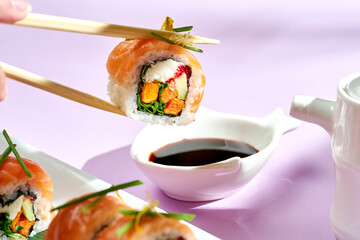 Sushi roll with salmon, cream cheese, onion and sweet potato. Bright backgrounds. Hard shadows, selective focus.