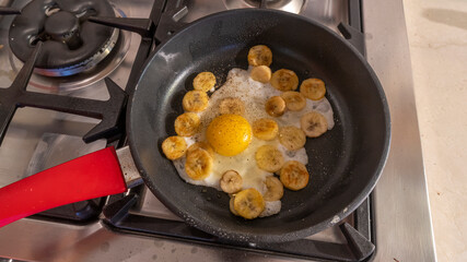 Cooking process of fried bananas with scrambled eggs. Fried Banana with eggs in hot pan.