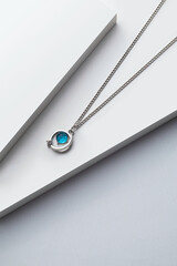 Silver chain necklace with blue diamond pendant on white background
