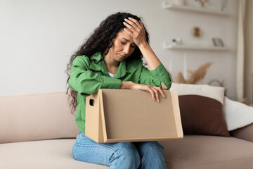 Frustrated Woman Buyer Unpacking Cardboard Box Siting On Couch Indoor