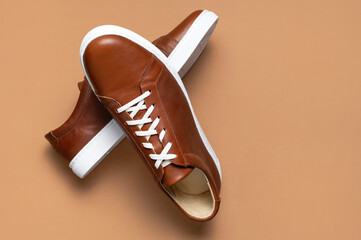 Leather brown men's sneakers with white laces and rubber soles on beige background. Flat lay top...
