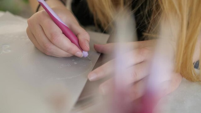 closeup of young female with long hair doing parchment craft with pen