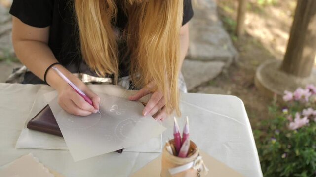 wide pan shot of young blonde female embossing parchment craft in garden